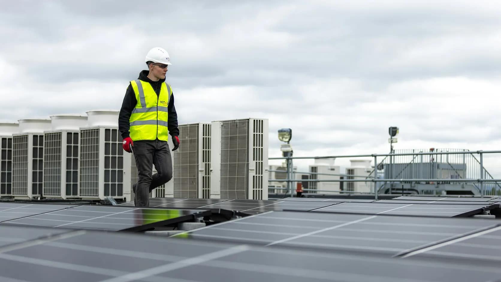 Instalação de climatização | Schaltz Engenharia Técnico com equipamento de segurança na cobertura ao lado de condensadoras de climatização