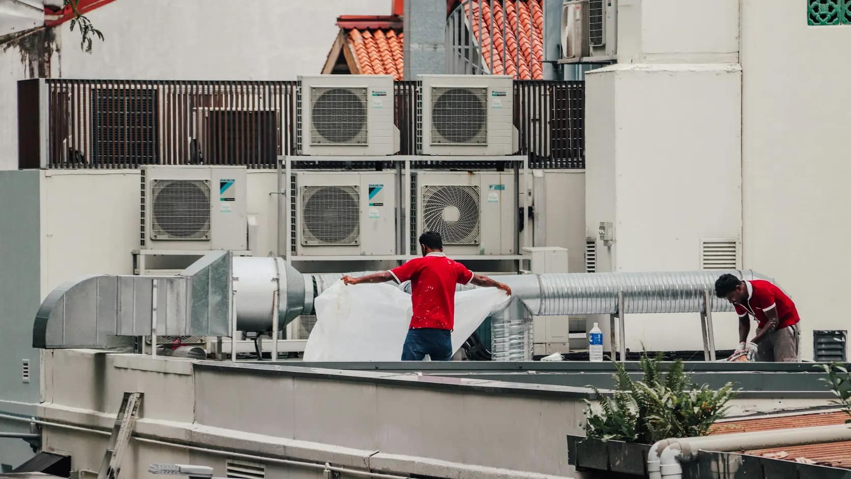 Manutenção de climatização | Schaltz Engenharia Técnicos trabalhando na cobertura junto a unidades condensadoras e dutos
